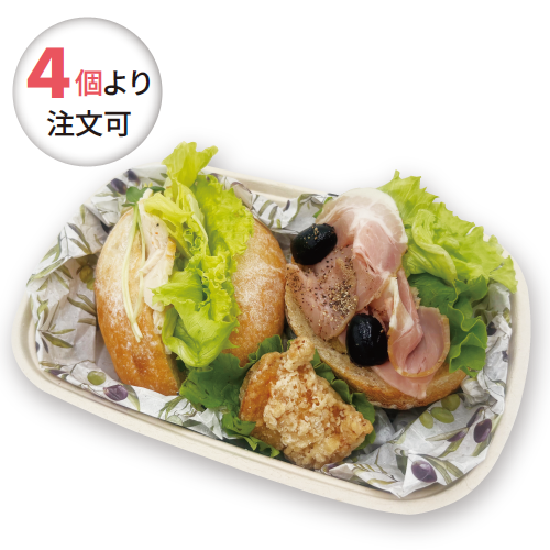 Lunch tray with lettuce-wrapped sandwich, ham, olives, and a piece of fried chicken; circular badge reads '4個より 注文可' (minimum order from 4)