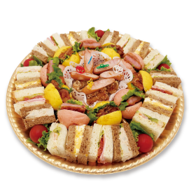 Platter of assorted finger sandwiches arranged in a circle with colorful fillings and greens.