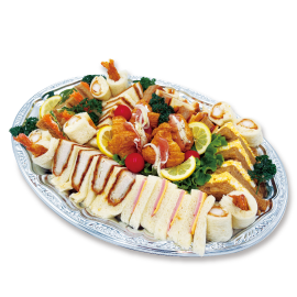 Assorted finger foods on a decorative platter: crustless sandwiches, croissant rolls, fruit, and garnishes.